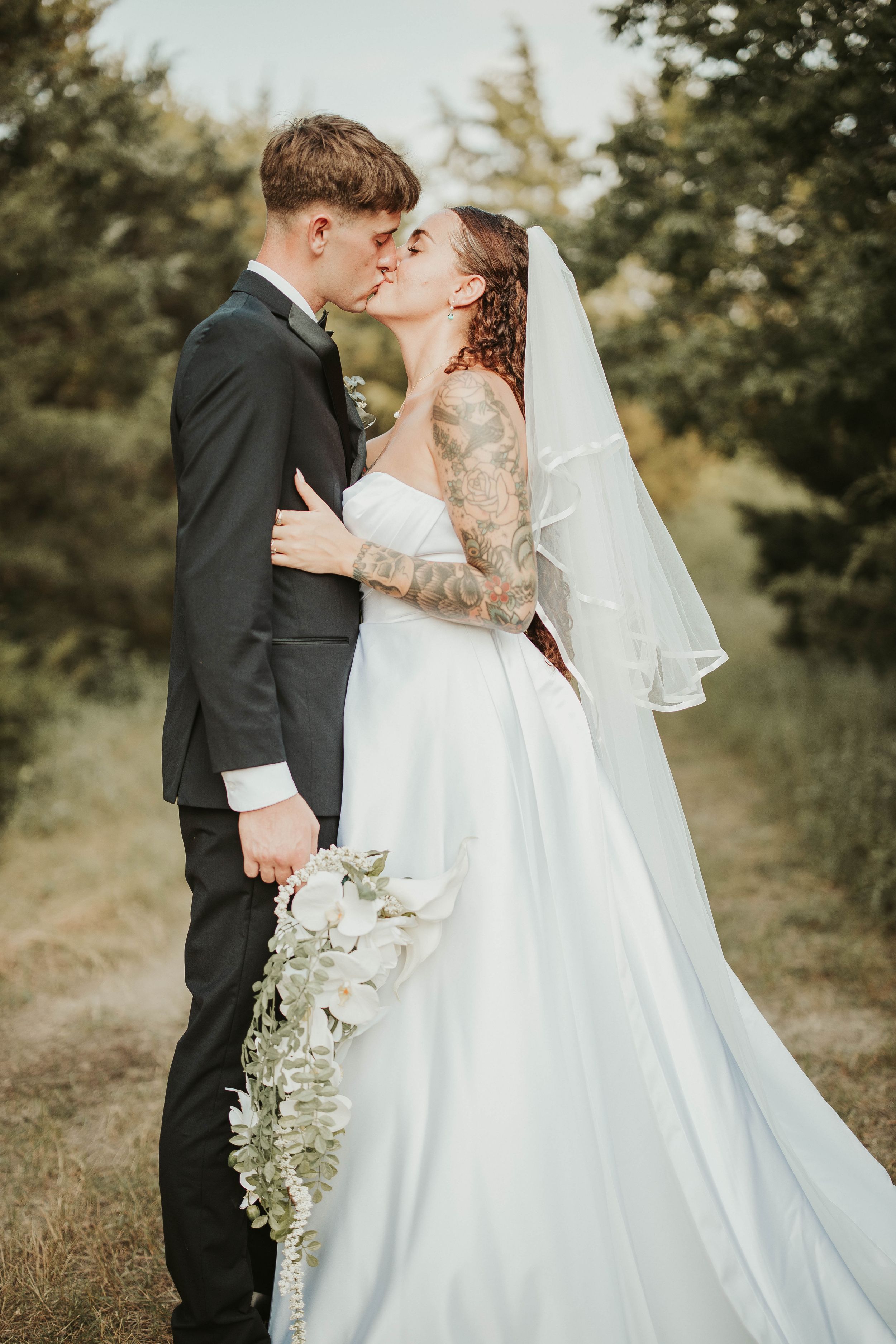Beautiful outdoor wedding portrait featuring a classic white gown and natural greenery bouquet.