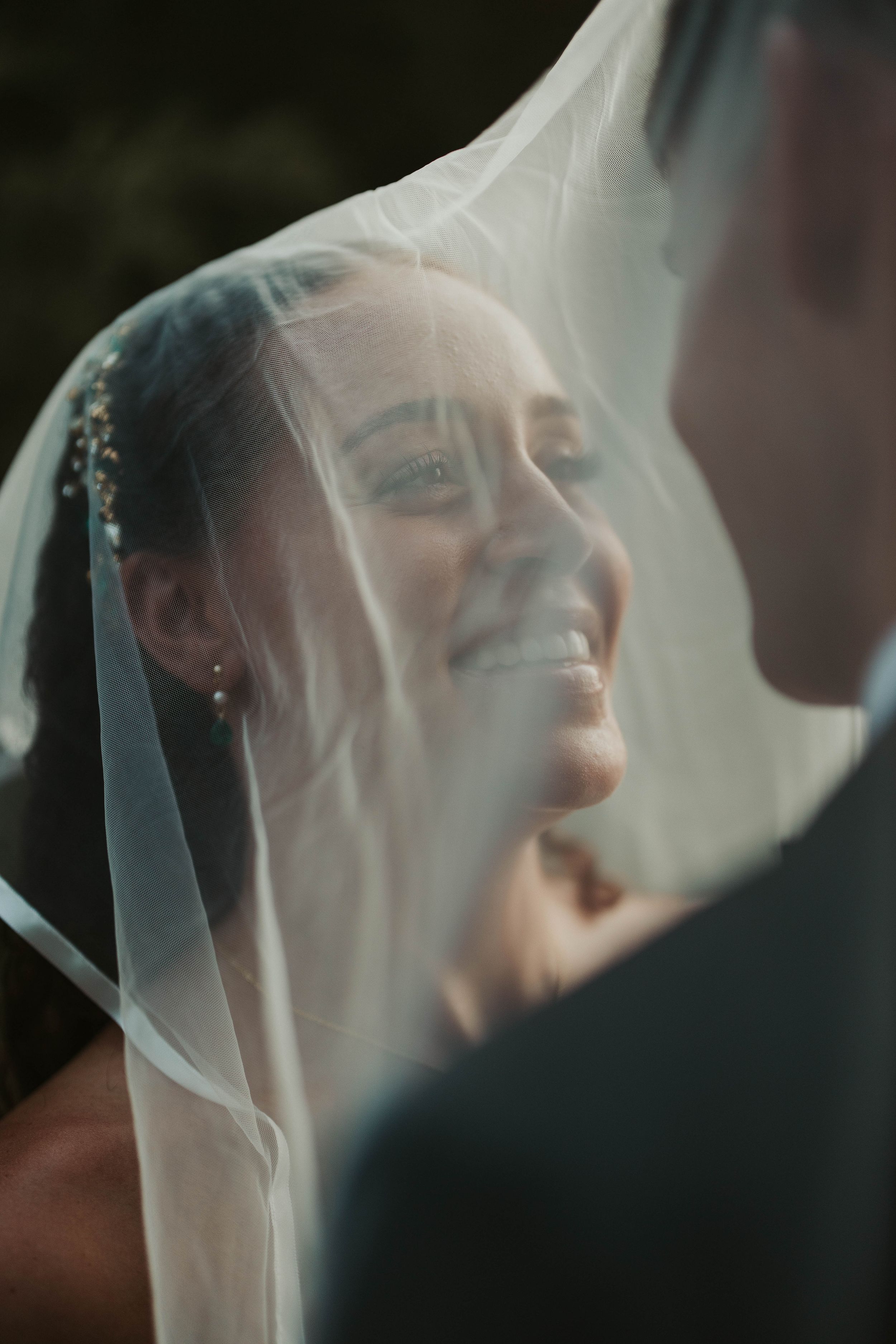 Close-up wedding portrait through sheer veil fabric creating ethereal lighting effects.