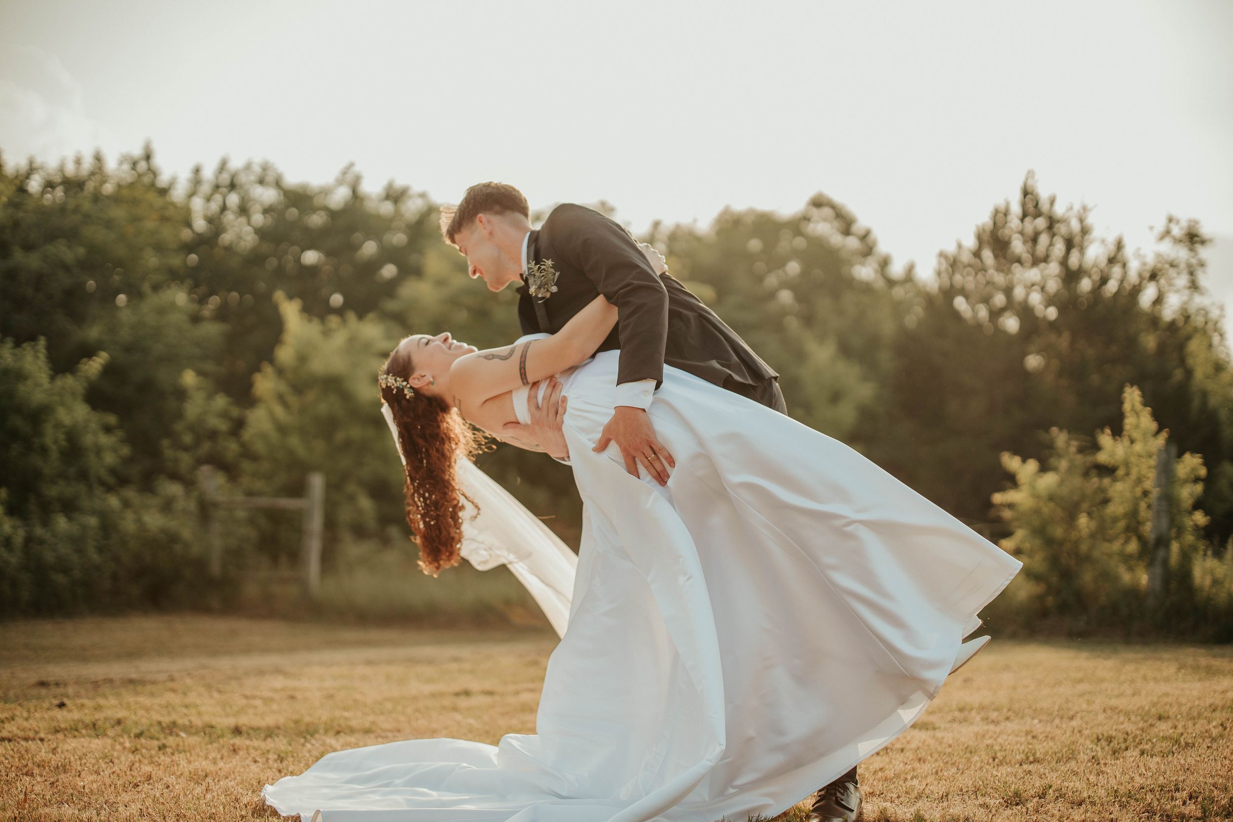 Candid wedding photograph showing movement of dress and veil in outdoor setting.