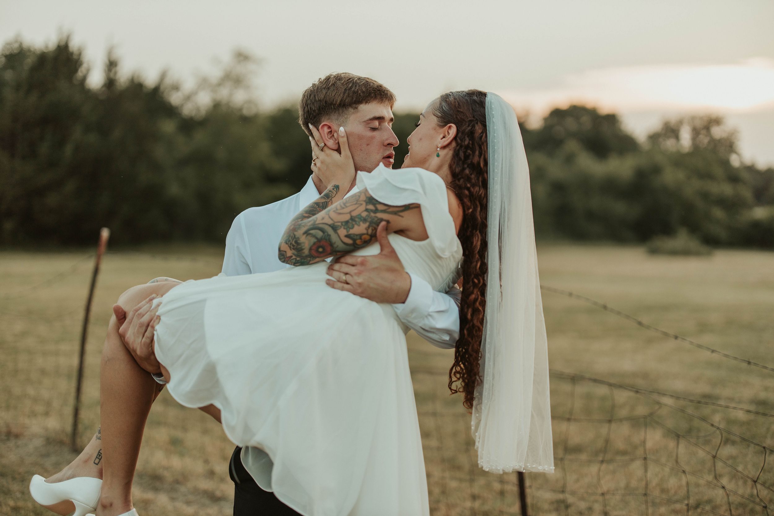 A joyful moment captured outdoors as a couple celebrates their wedding day in a grassy field.