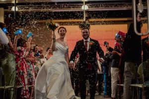 Newlyweds celebrate amidst shower of confetti at indoor wedding reception.