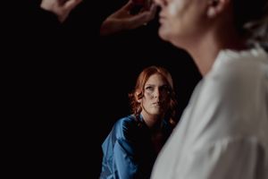 Intimate moment captured in dramatic lighting during wedding preparations.