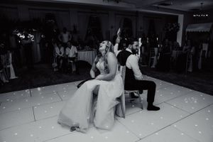 Black and white photo of wedding couple playing fun party game on illuminated dance floor.