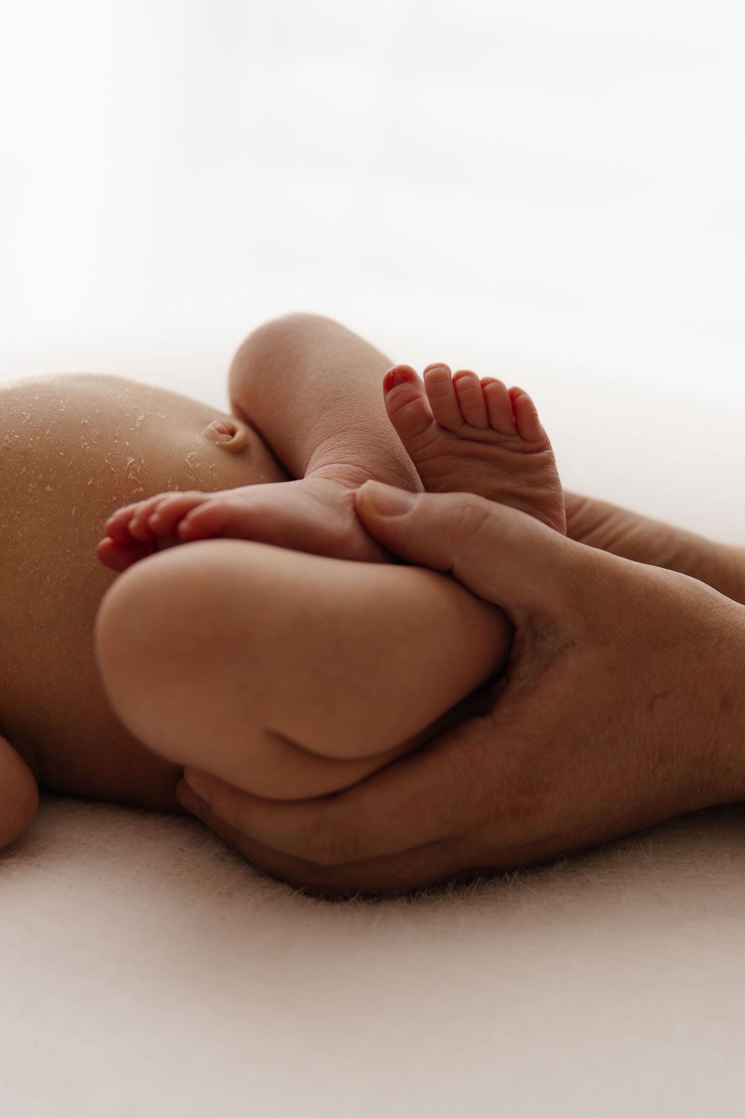 A close-up black and white portrait of a newborn baby being gently held.