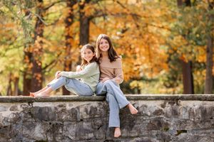Two girls sitting barefoot on stone wall surrounded by colorful autumn foliage at The Surrey-Williamson Inn in Saratoga Springs, NY.