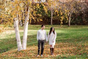 Couple holding hands walking through autumn park with yellow birch trees and fallen leaves in Congress Park in Saratoga Springs, NY during .
