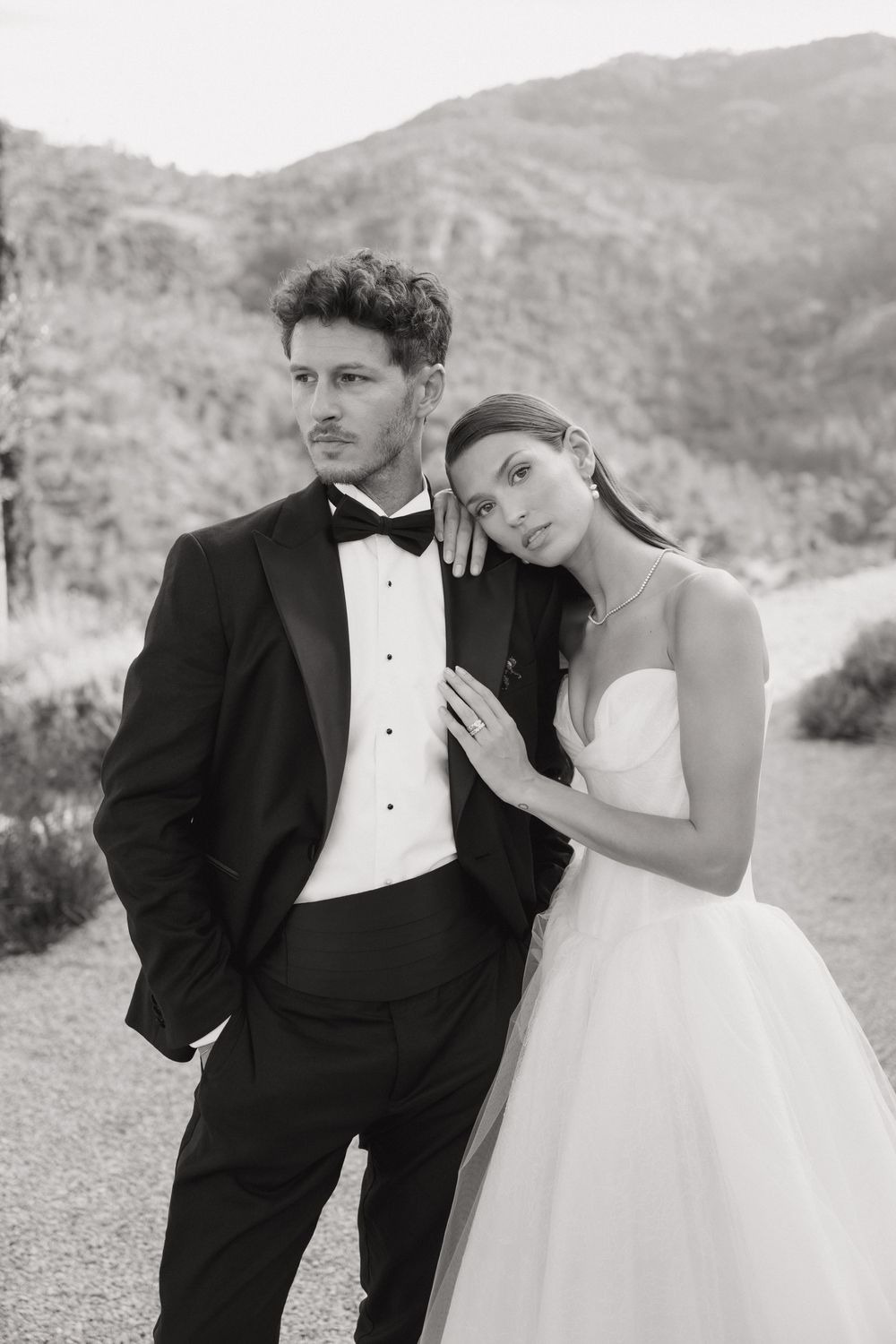 Black and white wedding portrait series showing couple in formal attire posing together against mountain backdrop.