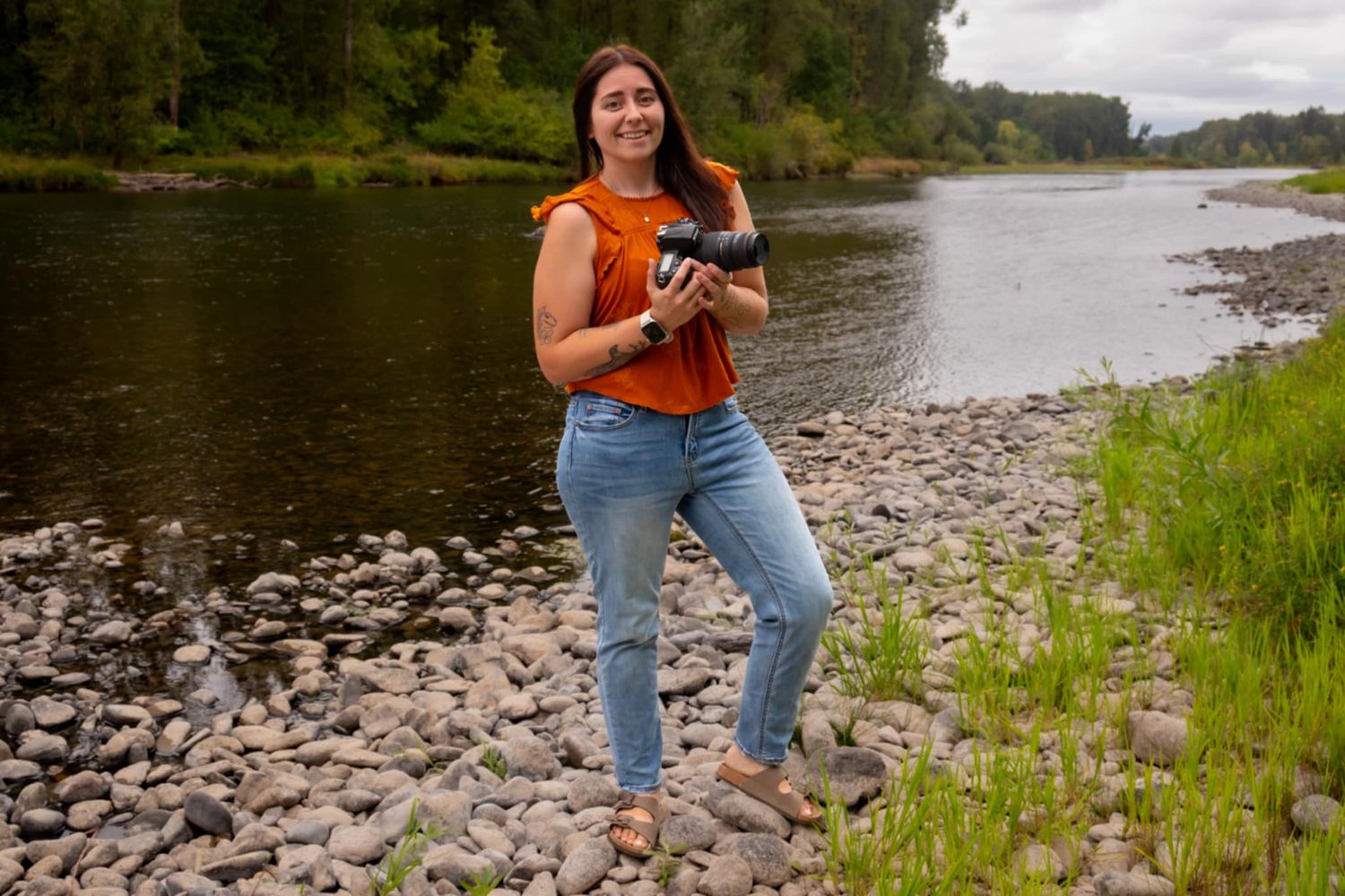 Professional branding photo of a photographer in a red shirt, holding a camera with a soft smile