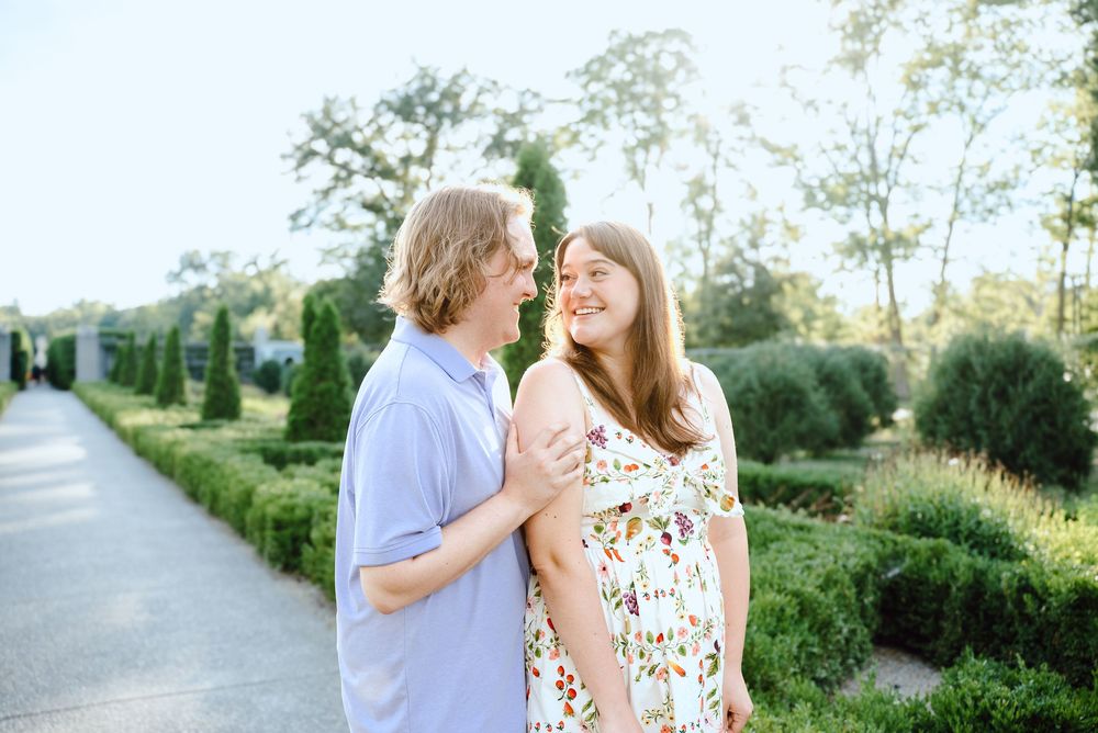 Couple enjoying a romantic sunset walk in a lush green garden path.