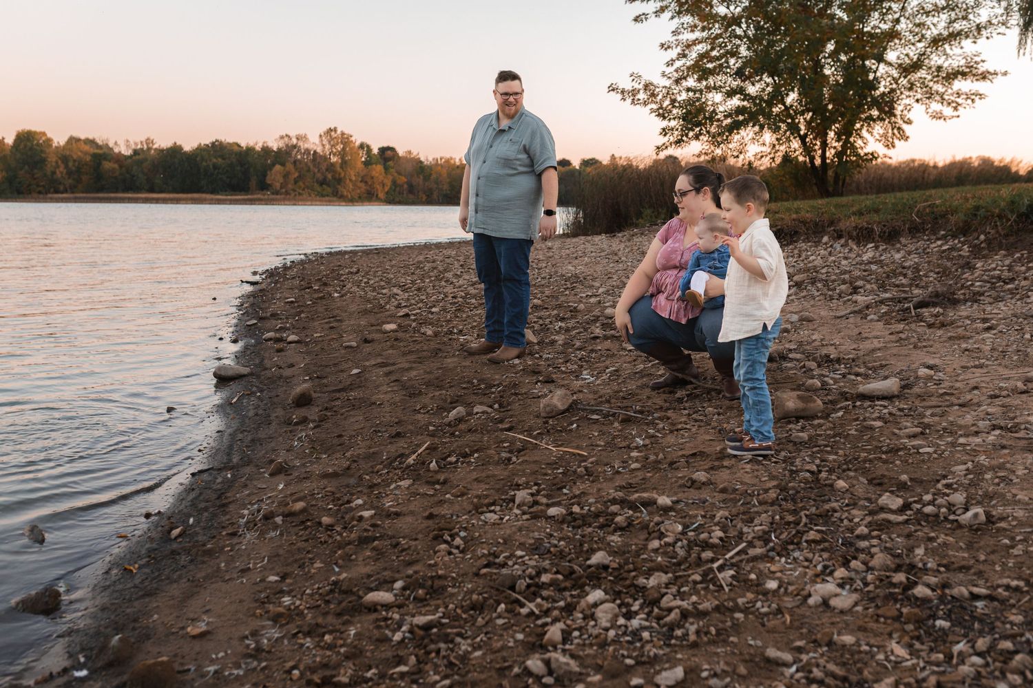 Boy picking white flowers with parents at sunset