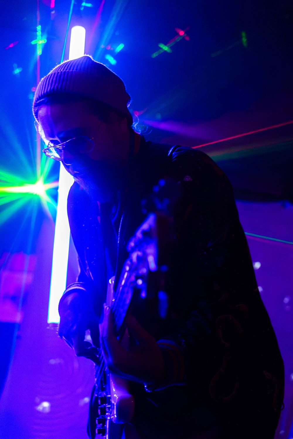 A colorful and dark photo of a bass guitar player.