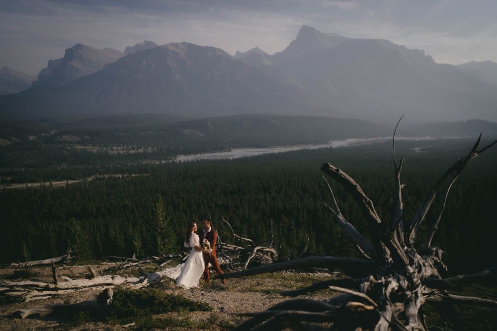 Wedding portrait silhouetted against mountain range and lake vista at sunset.