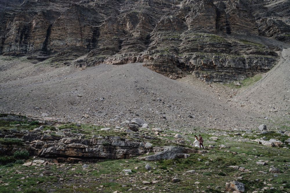 Dramatic rocky mountain landscape with green vegetation and scree slopes.