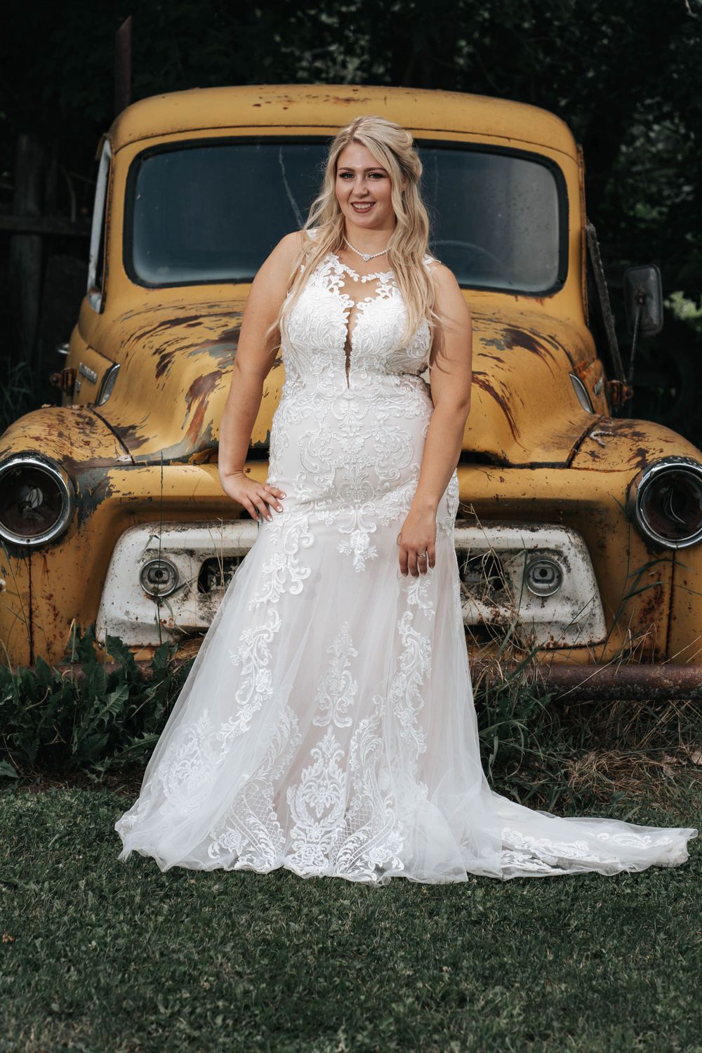 Wedding photo featuring a vintage yellow truck and elegant white lace dress.
