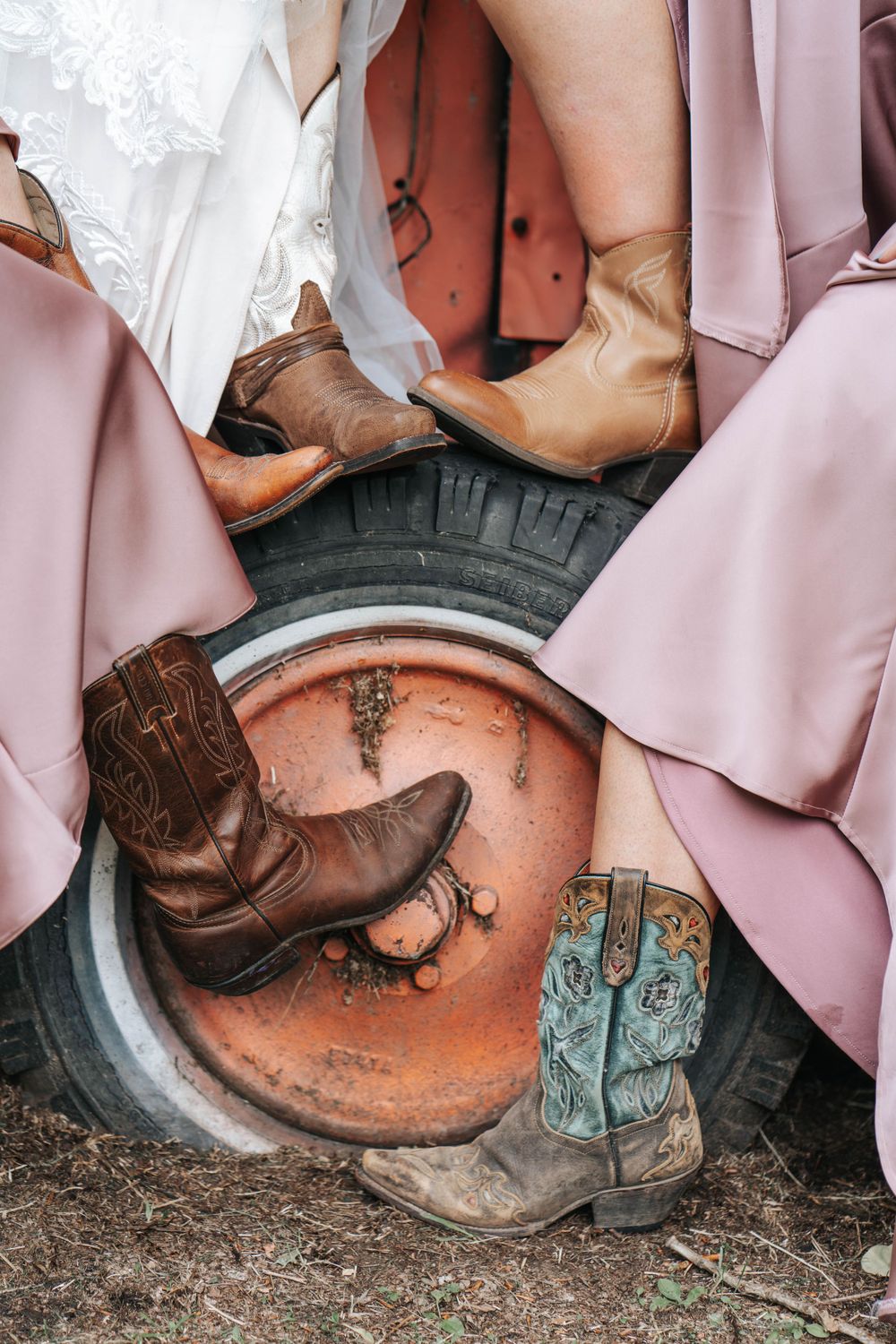 Various cowboy boots arranged artistically with pink and white dress fabrics.