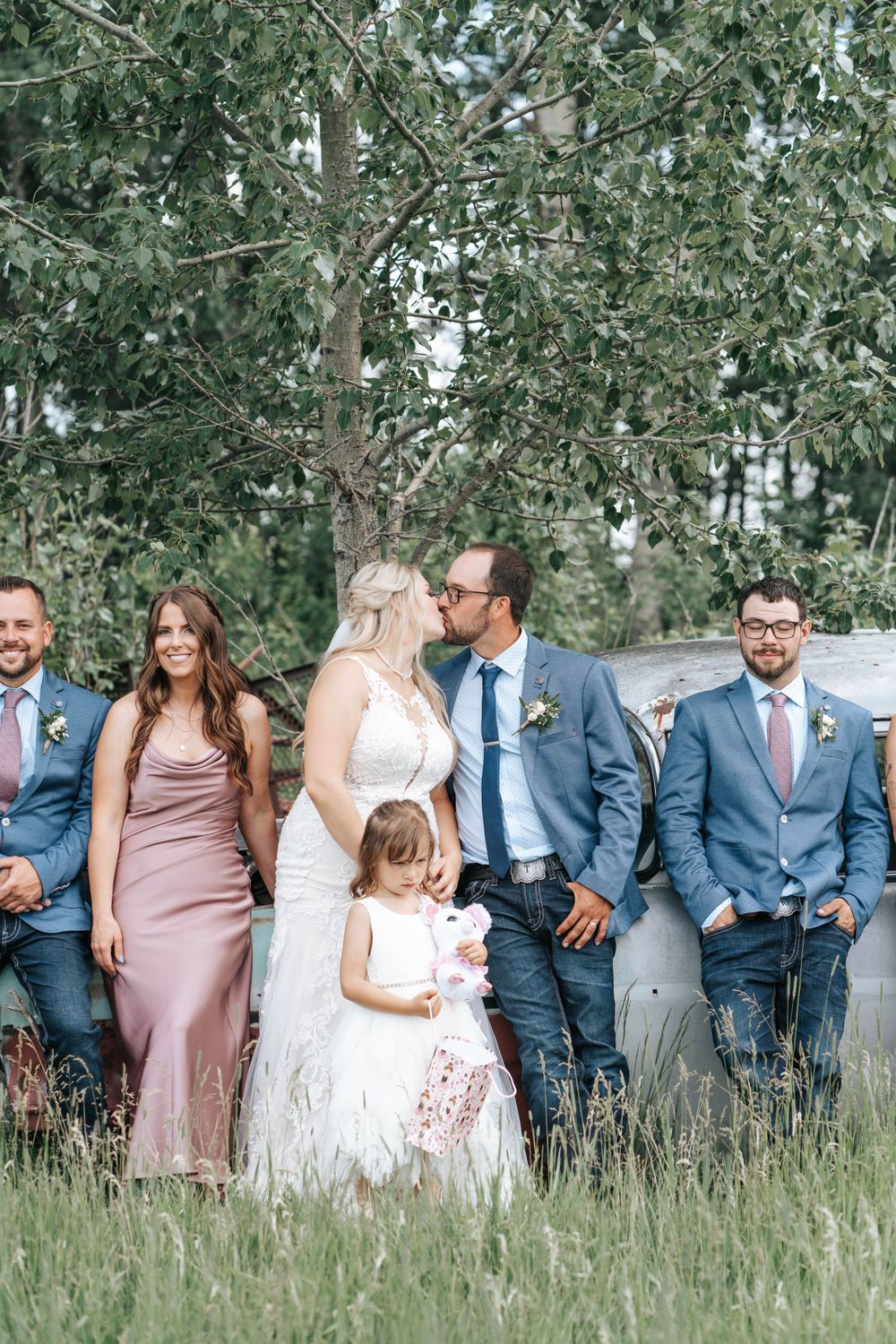 Wedding party poses together in coordinated attire against a backdrop of aspen trees.