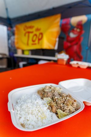 Several white takeout containers filled with rice and various dishes are arranged on a bright orange surface.