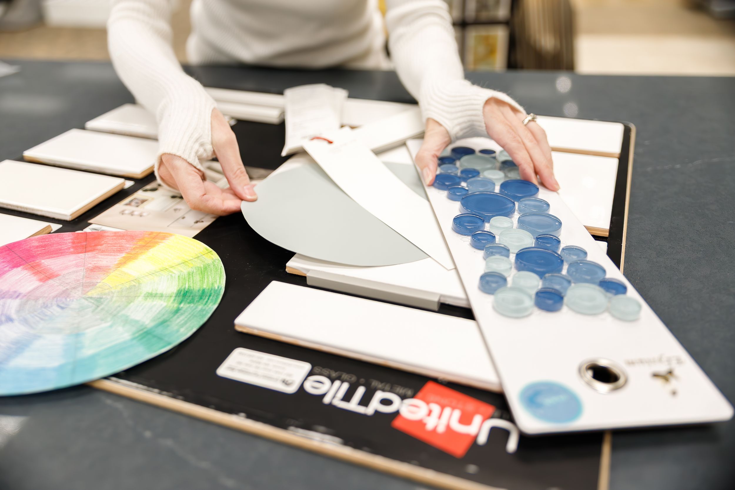 Students work with color wheels and design materials spread across tables in an art classroom setting.