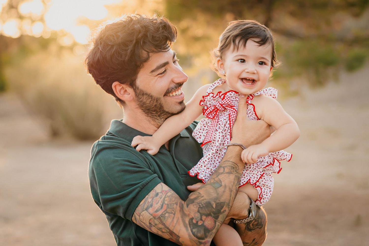Niña de un año con su padre en un entorno natural con árboles al atardecer durante una sesión de fotos familiar