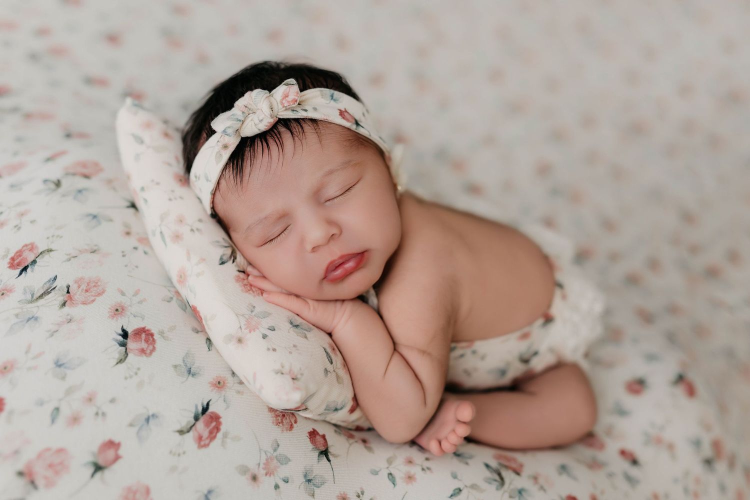 Sesión de fotos de recién nacido con fondo floral, mostrando al bebé en un pose adorable.