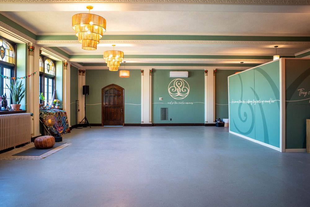 Empty dance studio with mint green walls, decorative lighting fixtures, and hardwood floors Quad Cities Real Estate Photography