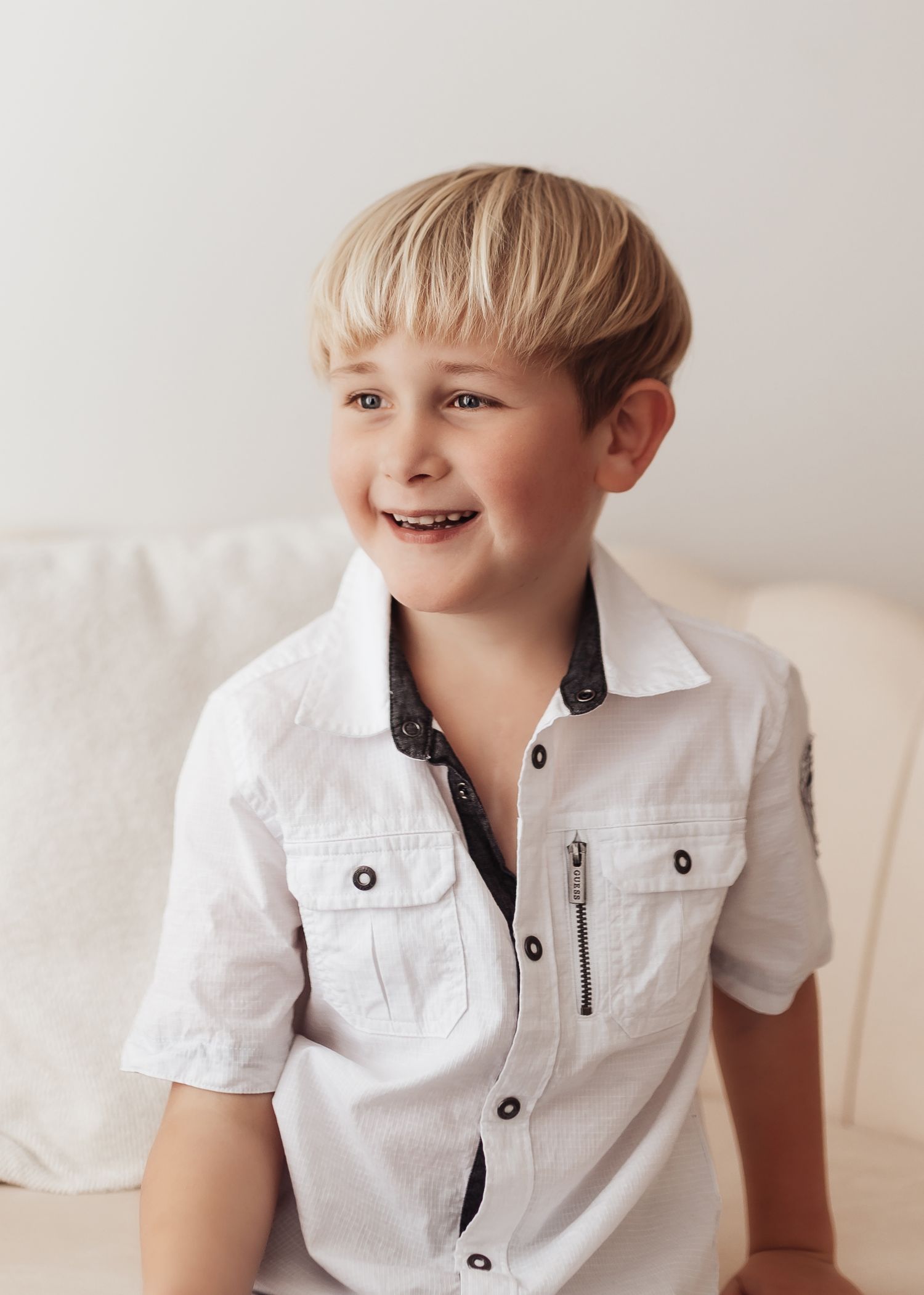 Young child in white button-up shirt shown in four candid poses against light background.