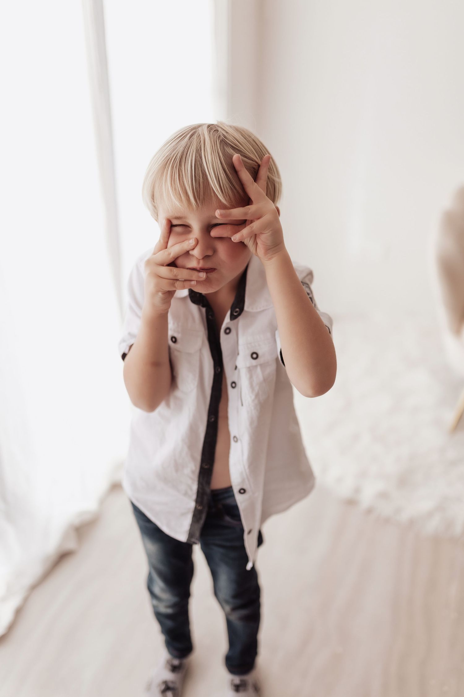 A sequence of playful photos showing someone in a white button-down shirt and jeans covering their face with hands.