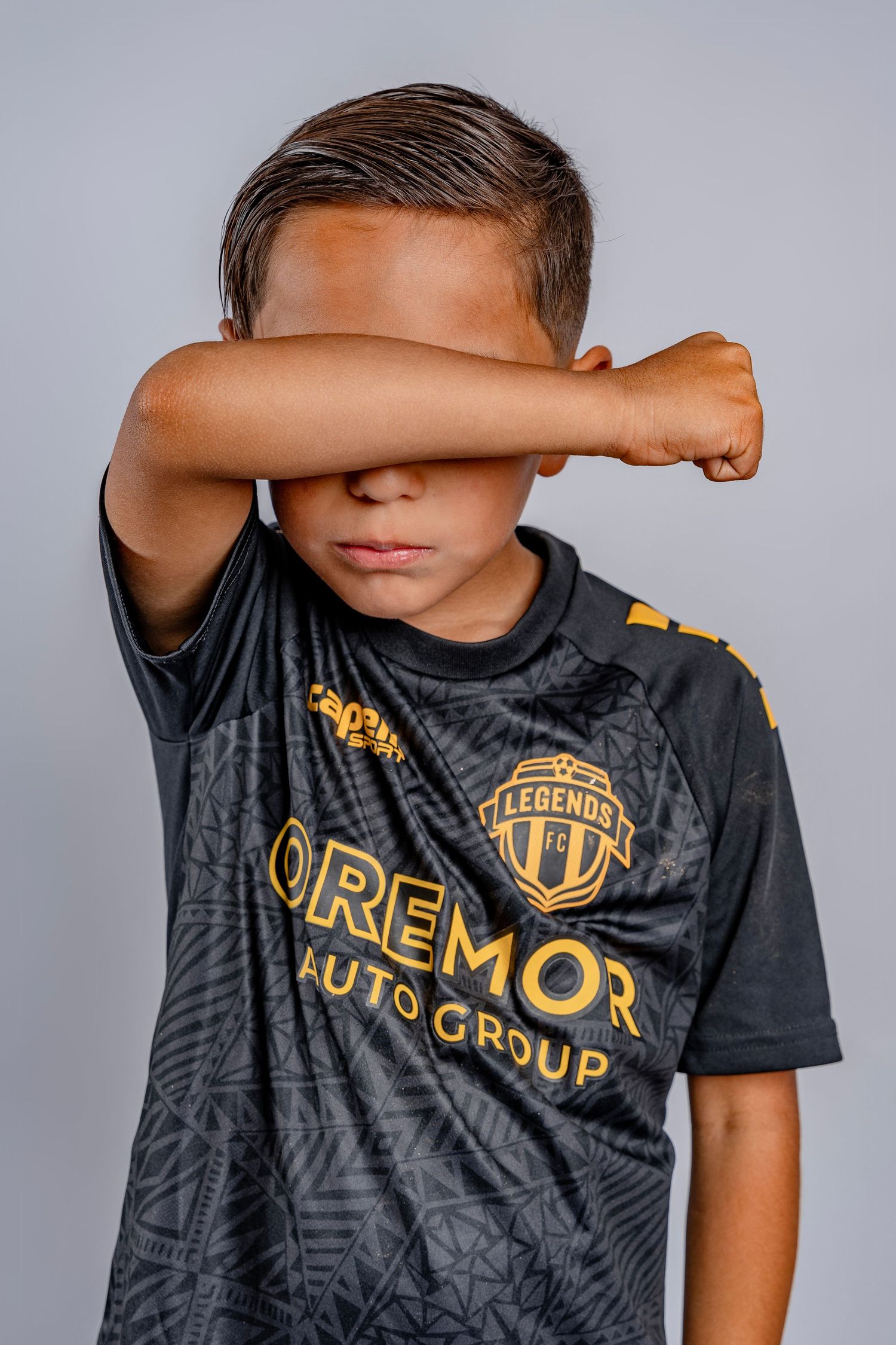 Young athlete in black and gold sports jersey strikes dramatic poses against gray background.
