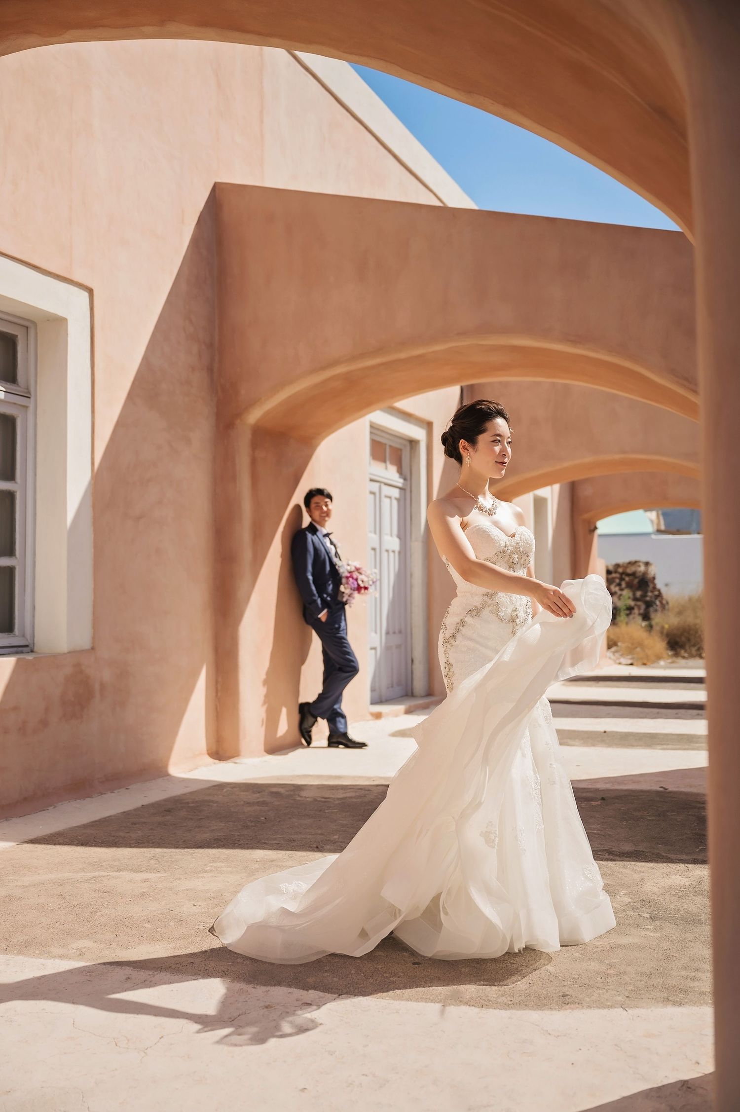 Artistic wedding portrait in Mediterranean architecture with arched doorways and soft peach walls.