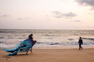 Dramatic beach photography with flowing fabric and figures against a sunset sky.
