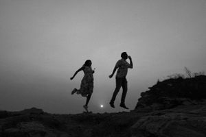 Silhouettes of people playing and jumping against a dramatic sunset sky.