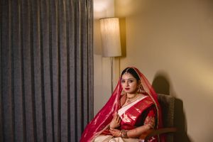 Traditional bridal portraits in red attire against warm indoor lighting.