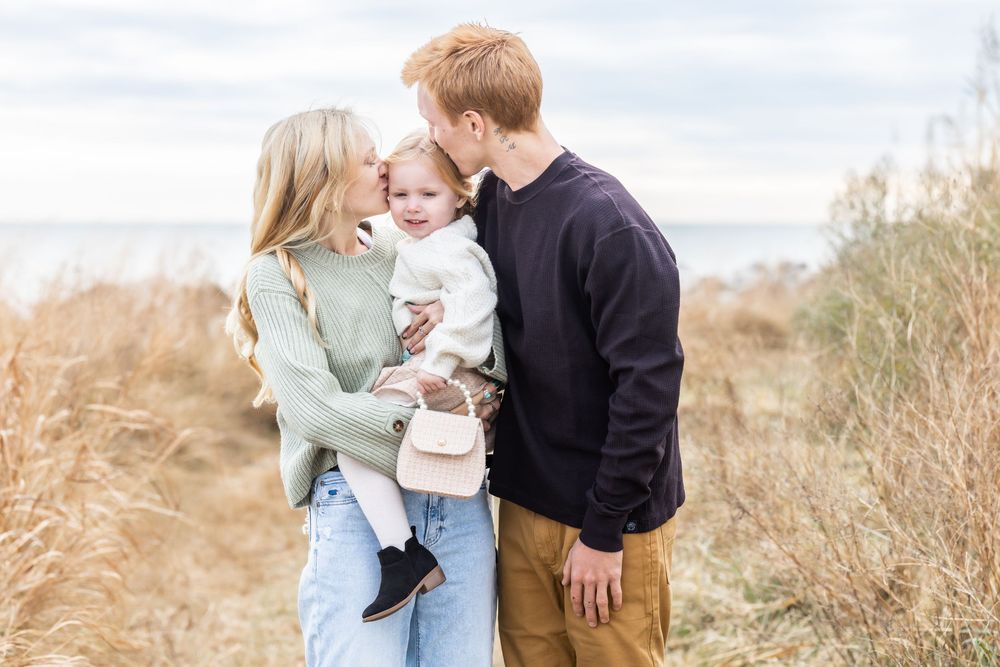 A couple embraces tenderly in a golden field during an autumn sunset engagement photoshoot.