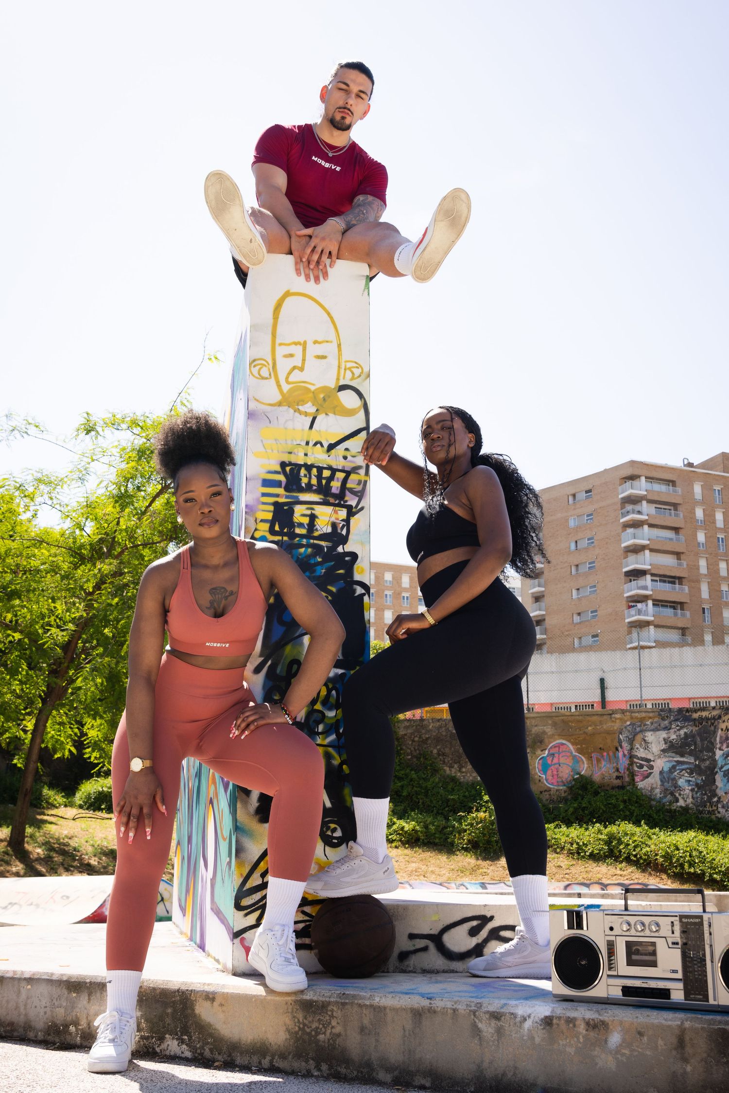 Urban dancers perform choreographed moves against graffiti wall in outdoor setting.