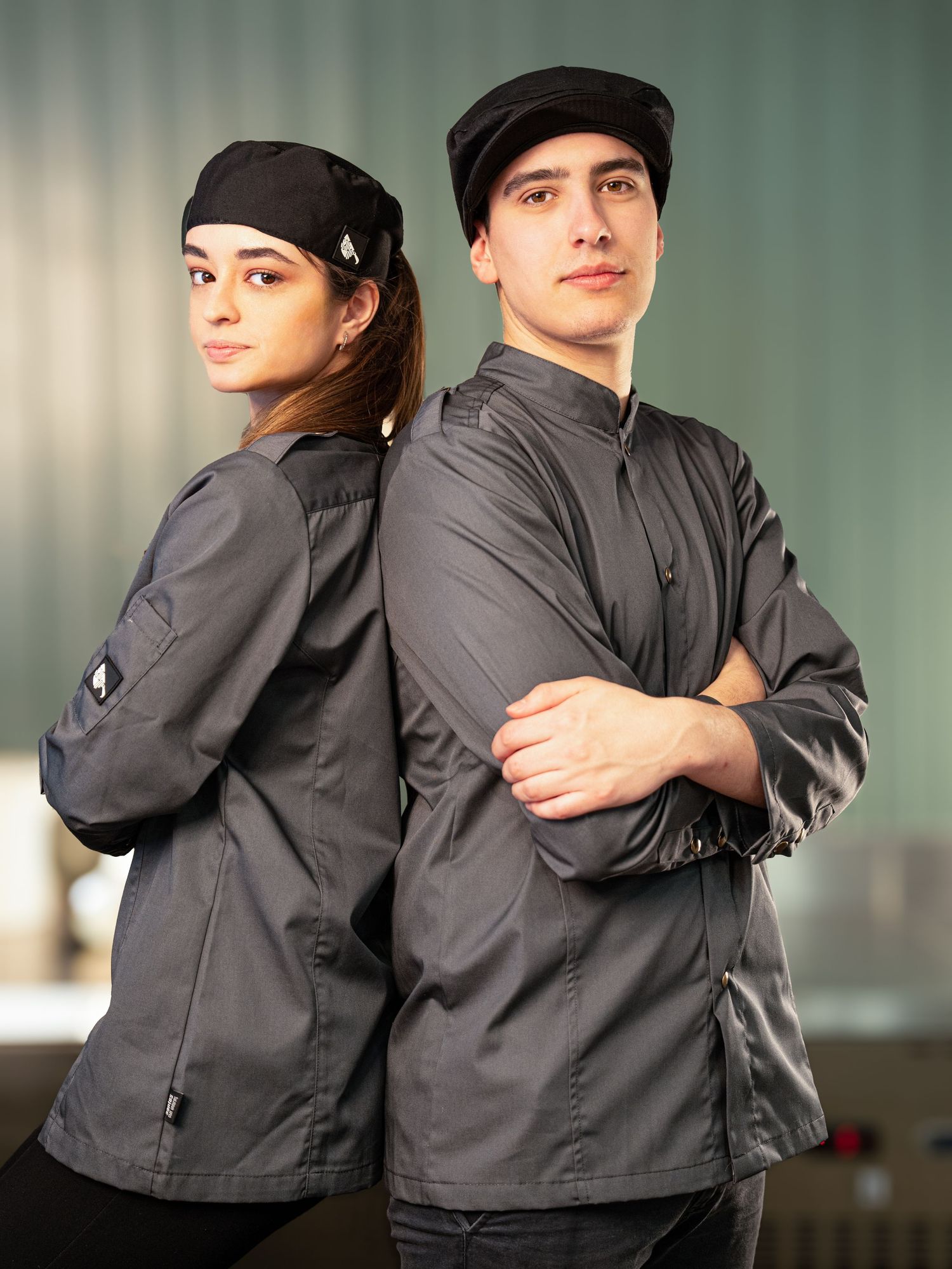 Two people in dark uniforms posing back-to-back in a professional setting.