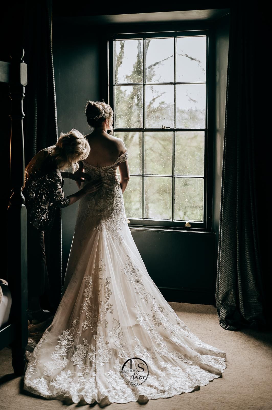 Two wedding gowns are showcased in an elegant white-framed doorway decorated with floral arrangements.