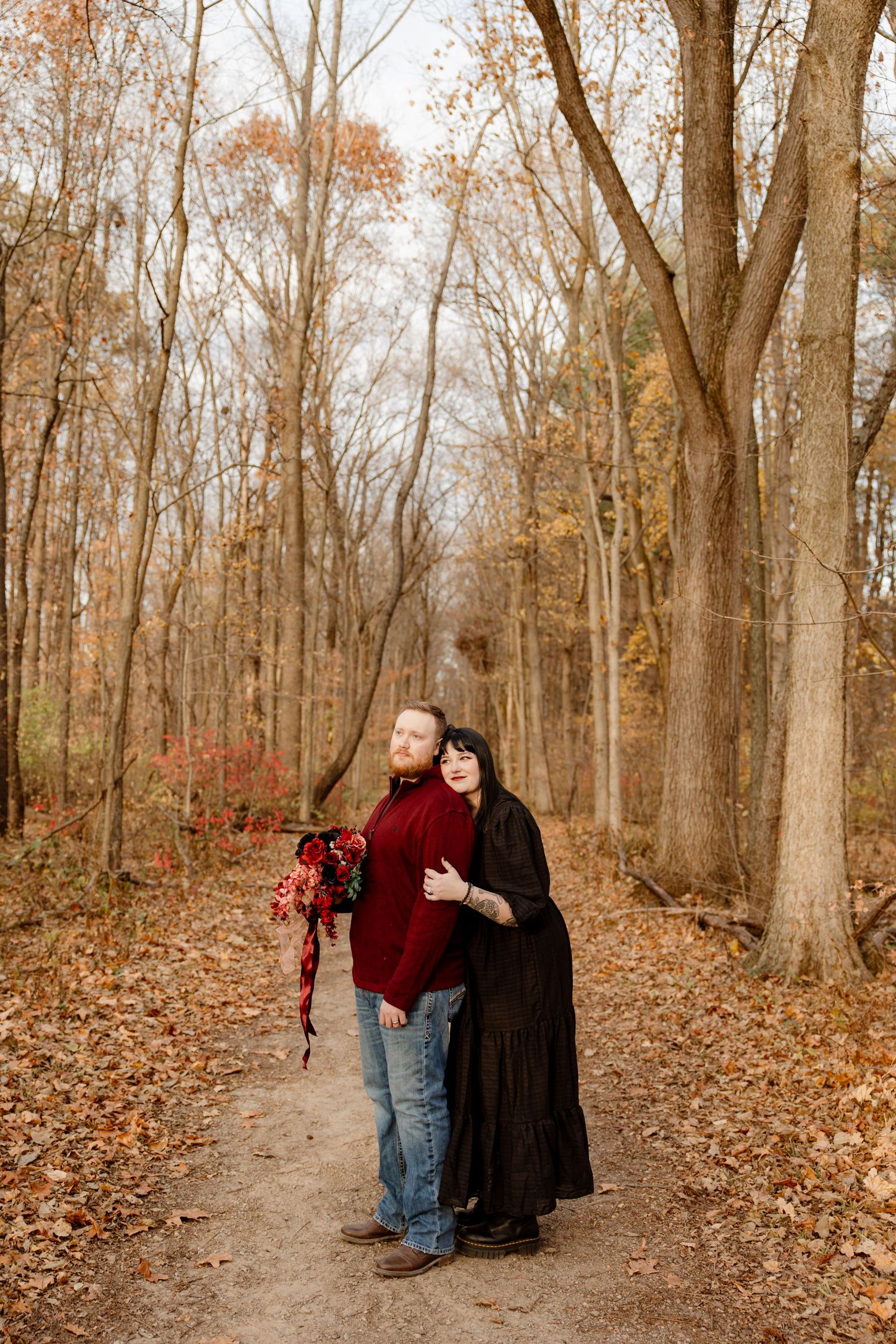 Couple walking together on an autumn trail covered in fallen leaves.
