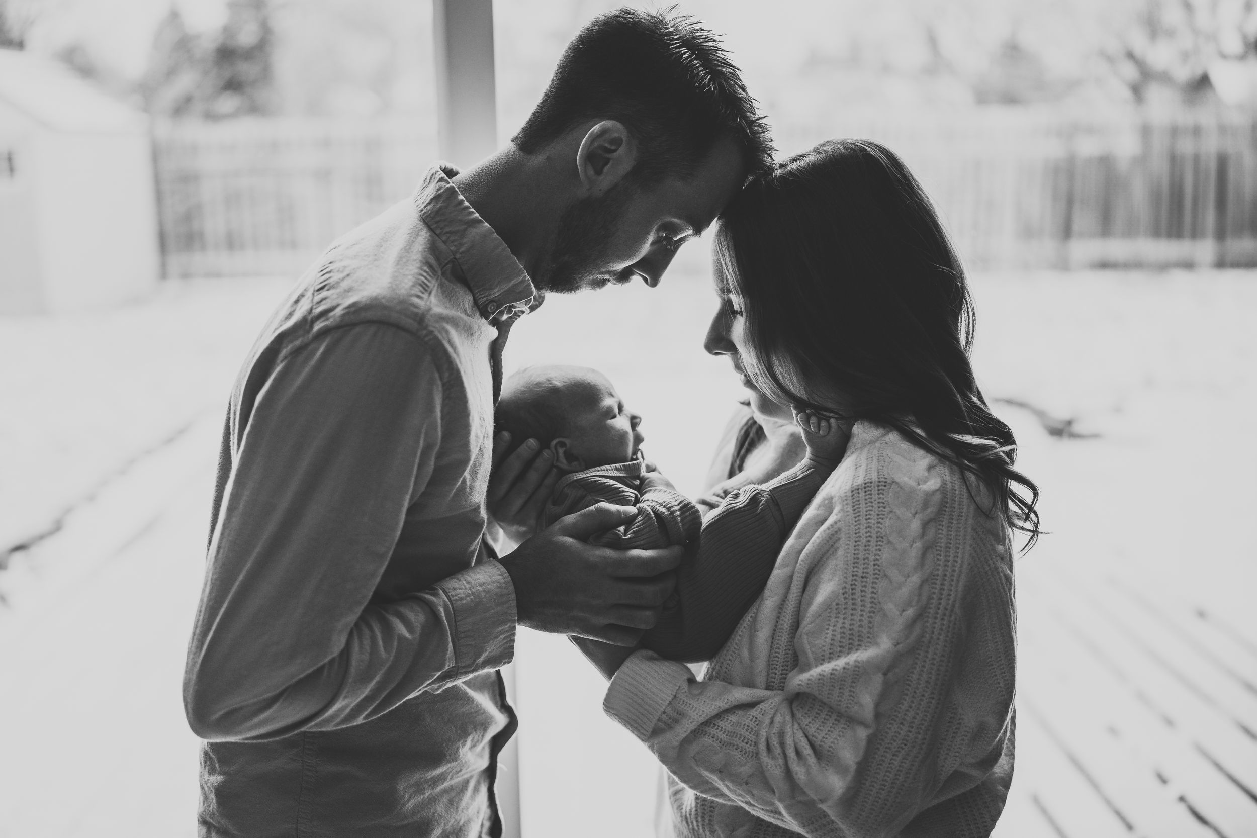 Black and white photo of parents gazing lovingly at their newborn.