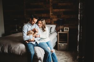 Intimate family moment captured in a bedroom with wooden accent walls.