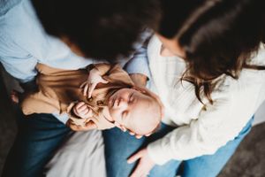 An overhead view of parents cradling their infant on their laps.