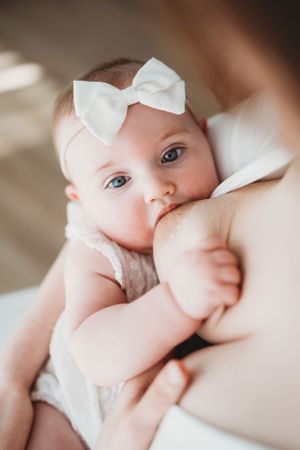 A sweet close-up of a baby wearing a white bow headband.