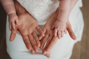 Close up of baby's tiny hands reaching out against white background.