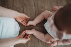 Hands reaching and touching on wooden floor surface.