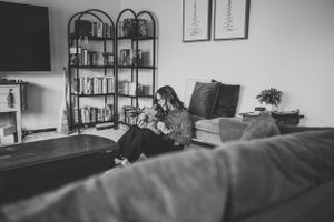 A couple sits together on a couch in a cozy living room with bookshelves.