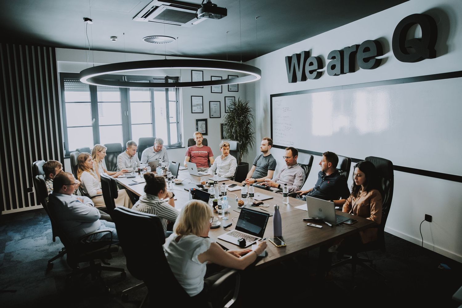 Business team meeting in modern office conference room with white walls and laptops.