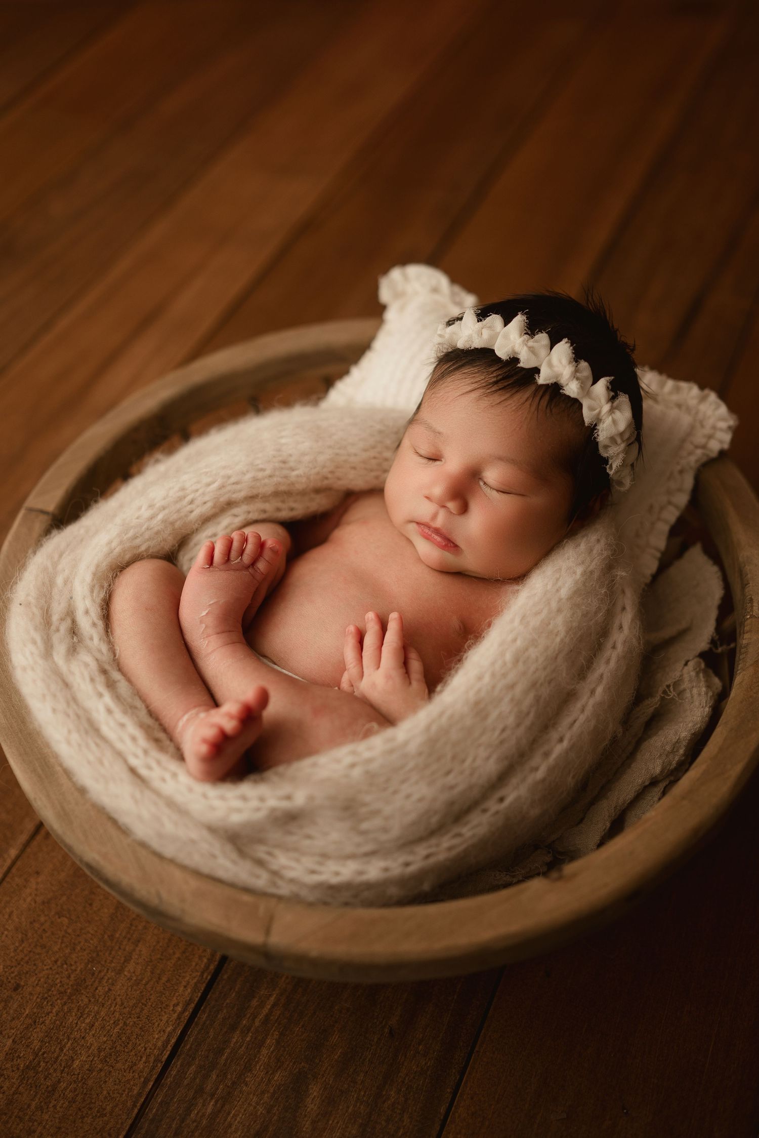 Newborn baby boy sleeps peacefully in wooden bowl during studio newborn session in Clarksville, Tennessee by Disney Magic Photography.