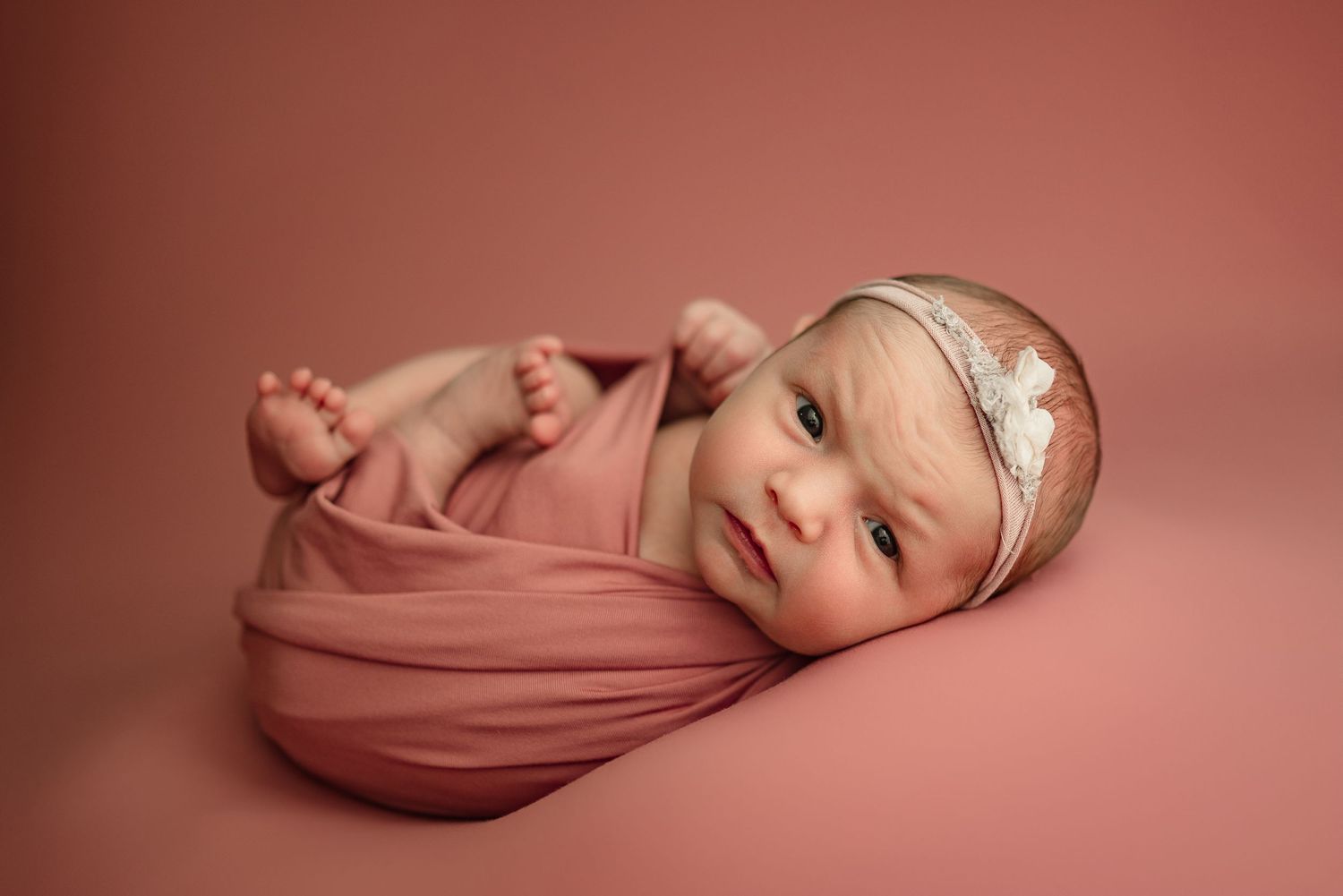 Baby girl gives stern look during studio newborn photography session at Disney Magic Photography studio in Clarksville, Tennessee