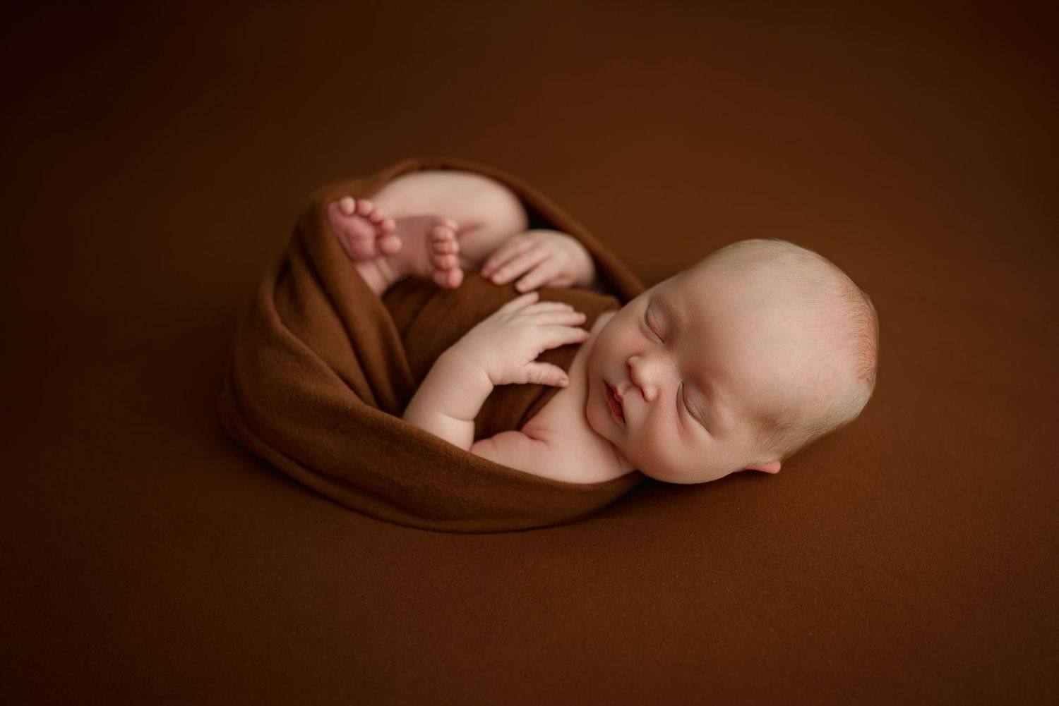 Newborn baby boy sleeps peacefully in bucket during studio newborn session in Clarksville, Tennessee by Disney Magic Photography.