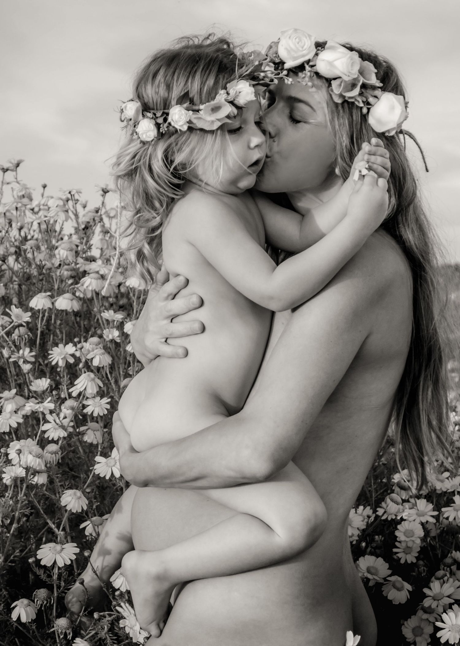 Artistic black and white portrait of intimate embrace among white flowers.