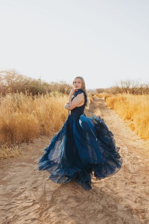 A navy tulle dress creates movement against sandy terrain and golden brush.